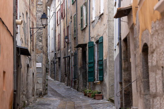 Entrevaux, France -  A narrow old street with shuttered buildings and wall lanterns in the historic town.