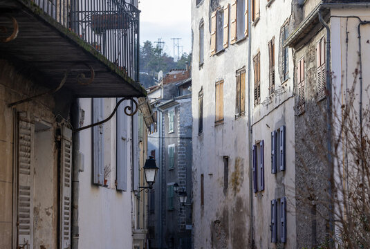 Entrevaux, France -  A narrow old street with tall shuttered buildings and wall lanterns.