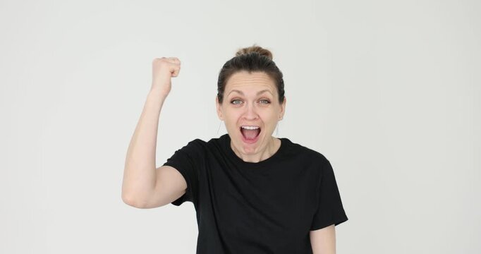 Woman in plain black T-shirt angrily hits fists against sides of head. Female accuses companion of making foolish mistake against white background