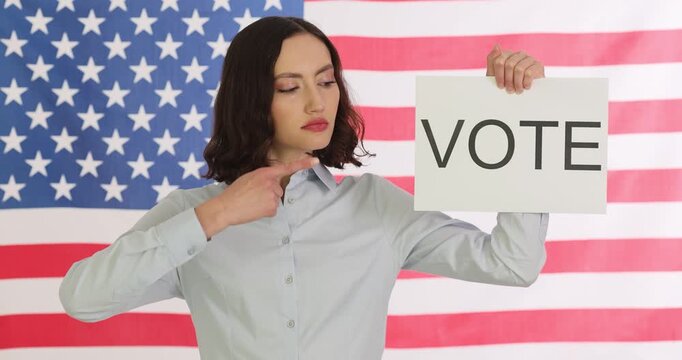 Serious woman politician canvasser shows sign with word Vote. Female encourages responsible citizens to participate in important election. Slow motion