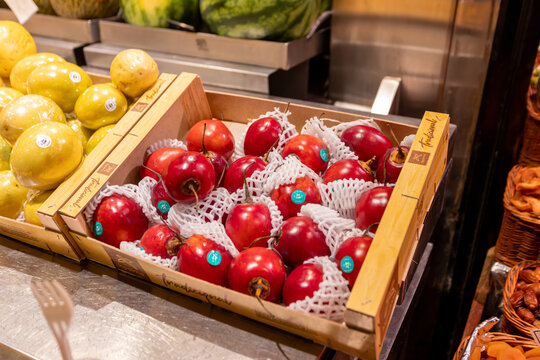 Barcelona, Spain - January 3, 2026: A red tamarillo with a Zespri sticker rests in a wooden crate at La Boqueria market.