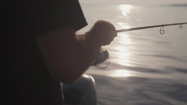 Amateur angler fishing on the river from a boat at sunset