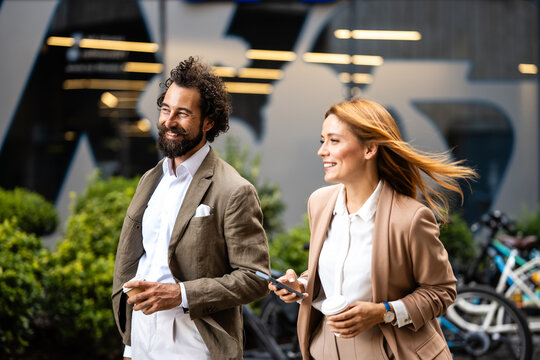 Business people walking and talking outdoors in urban setting
