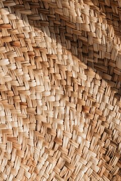 Closeup of woven raffia basket texture illuminated by warm afternoon light in a bohemian living room setting with natural palm fibers