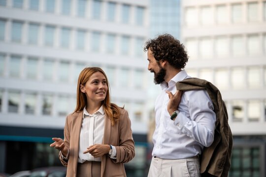 Businesspeople talking and smiling outside office building
