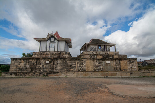 Panoramic view of the traditional royal buildings inside the Rova of Antananarivo, the historic royal palace complex of Madagascar, surrounded by ancient stone walls under dramatic clouds.