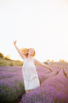 Smiling 38 year old woman dancing in lavender field, warm sunset light, confidence, natural beauty, self acceptance, joyful lifestyle