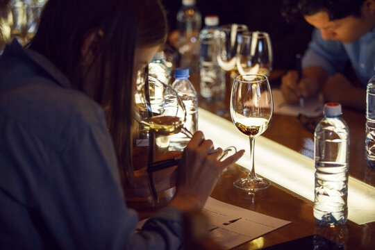 Elegant White Wine Glass In Focus During Indoor Sommelier Tasting Event With Connoisseurs