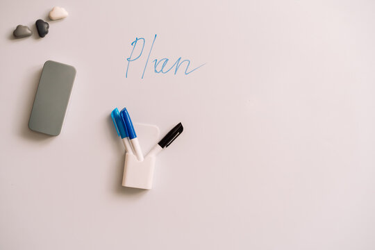 Whiteboard with handwritten Plan and markers below beside three small magnets.