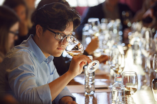 Korean Sommelier Engaged in White Wine Tasting Session at Degustation Event
