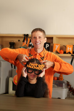 Father and daughter wearing Halloween party glasses and headband for autumn holiday celebration