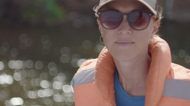Portrait of the woman wearing lifejacket and sitting in the boat moving on the river
