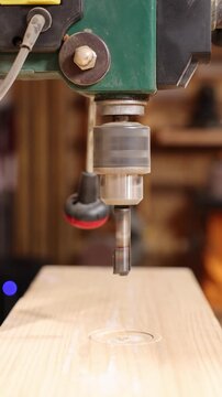 Close up of a drill press making a hole in wood