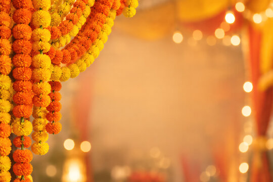 Vibrant yellow and orange marigold flower garlands hanging as traditional Indian festive decoration with soft glowing bokeh lights background