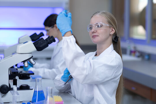 Women scientists conducting laboratory research with pipette and microscope for biotechnology, scientific experiment, medical analysis, microbiology, healthcare innovation, laboratory testing