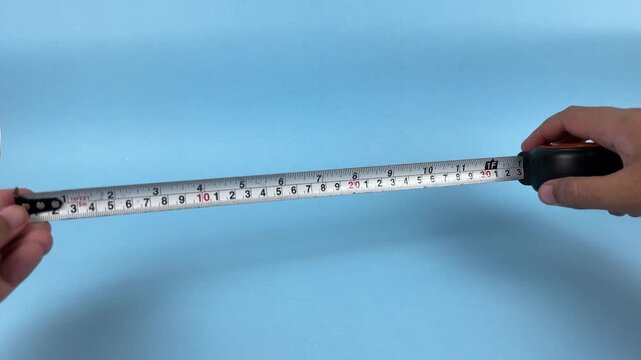Hands Extending Measuring Tape for Length Measurement on Blue Background
