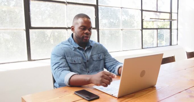 African American man discussing business strategy during video call at office desk