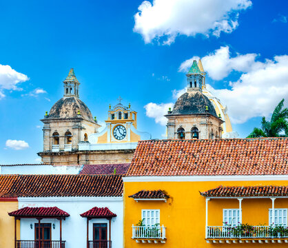 Historic domes and colorful colonial houses with terracotta roofs in Cartagena, Colombia, under a bright blue sky.