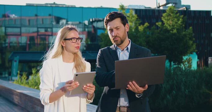 Portrait of business man and woman working remotely outdoors with laptop and tablet