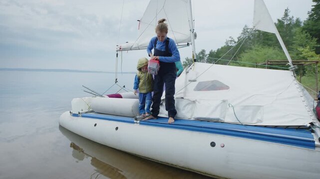 Woman with kid walk on the sailing boat beached on the wild area