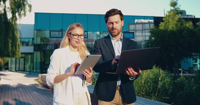 Business people walking with laptop and tablet in modern city