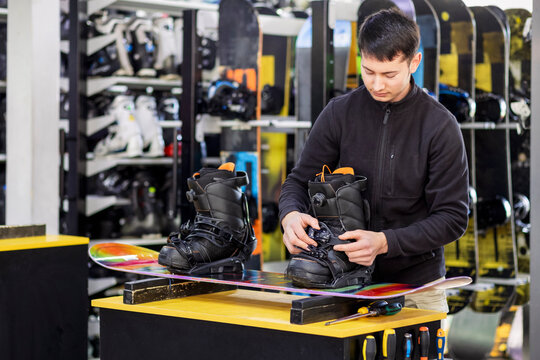 Snowboard boot Fitter or Ski Instructor adjusting Snowboard Boot and Binding, Preparing Equipment for Snowboarding on Winter Ski Resort. Snowboard Rental Equipment and Fitting service at Ski Resort.