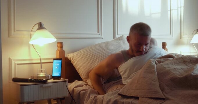 Young man wakes to a medication reminder on his phone and takes his morning pills from a weekly organizer.