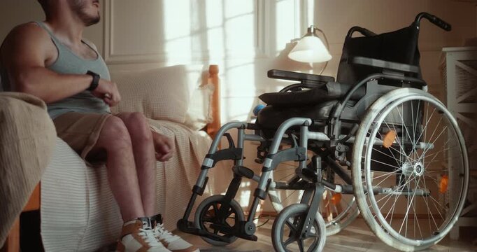Young man with a disability puts on his sneakers and transfers into his wheelchair, independently completing his morning routine at home.