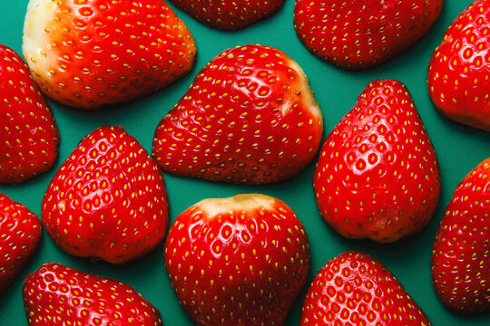 Glossy Red Strawberries on Teal Background