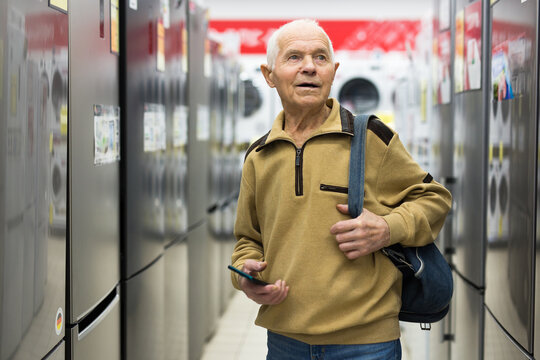 senor man pensioner buying fridge in showroom of electrical appliance store