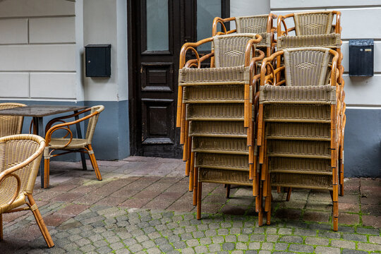 Stacked Wicker Chairs Beside a Quiet Caf&eacute; Entrance