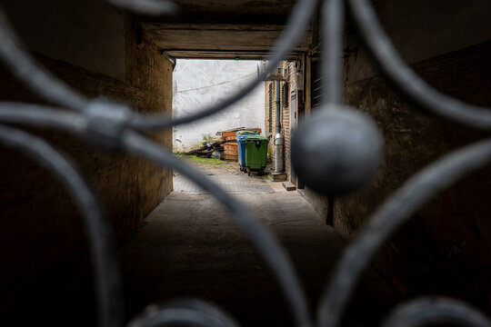 Metal Gate Frames Trash Bins in a Dark Urban Passage
