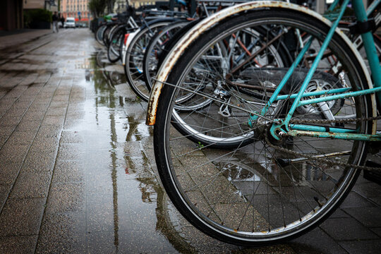 Parked Bicycles Along a Rain-Soaked Urban Sidewalk