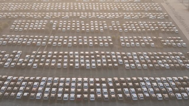 New car storage yard with thousands of vehicles arranged in organized rows for automotive logistics