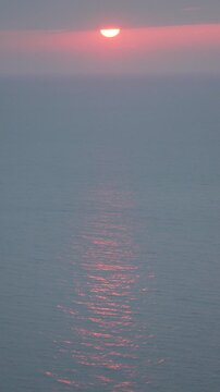 Sunset ocean horizon with a pink sky and calm water reflecting soft light for a serene and peaceful mood