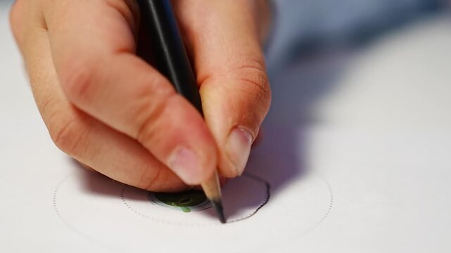 First grade student practices writing letters with pencil in workbook. Early literacy and handwriting skills develop with selective focus and shallow depth of field