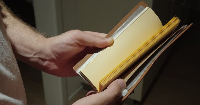 Hands flipping through blank pages of a leather notebook, representing empty notes, writing and new ideas.