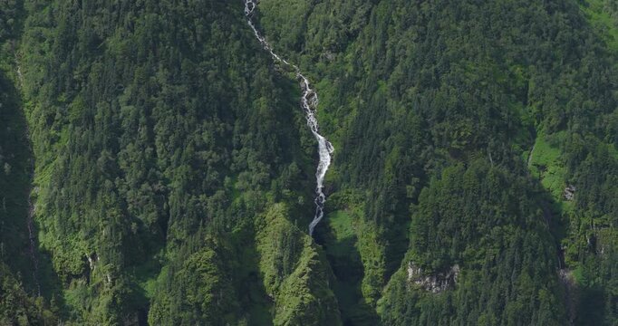 Badimalika Bajura Nepal, aerial shot of a long white mountain stream cascading down a steep, densely forested pine slope along the Birekhola Badimalika trekking route
