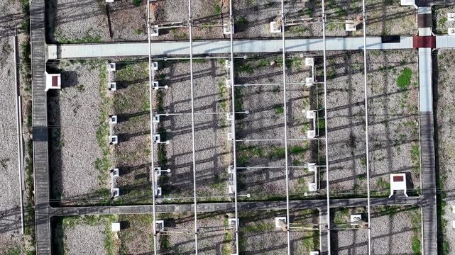 Top down drone shot of high voltage electrical substation showing grid layout lines insulators maintenance walkway