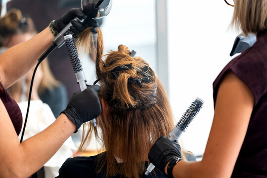 Hair stylists blow drying client's hair in a modern beauty salon