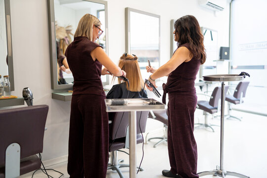 Hairdressers styling client's hair in a modern beauty salon, providing professional service