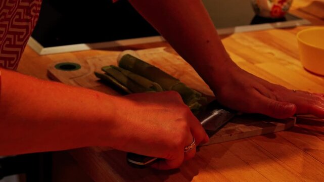 Woman cutting a fresh leek on a wooden board