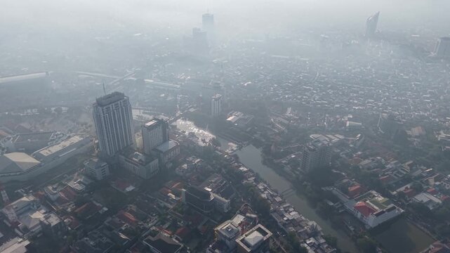 Mist blankets the city skyline. Buildings fade into haze, obscured by low clouds at Surabaya