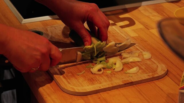 Woman's hands slicing fresh leek on cutting board