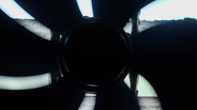 Front-facing close-up of industrial axial fan hub with silhouetted curved blades in tight symmetrical composition