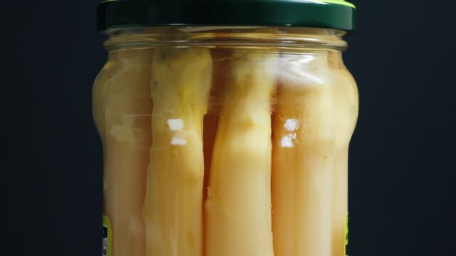 Close-up of pickled white asparagus spears in a glass jar, preserved vegetables in brine, a common canned food and gourmet appetizer.