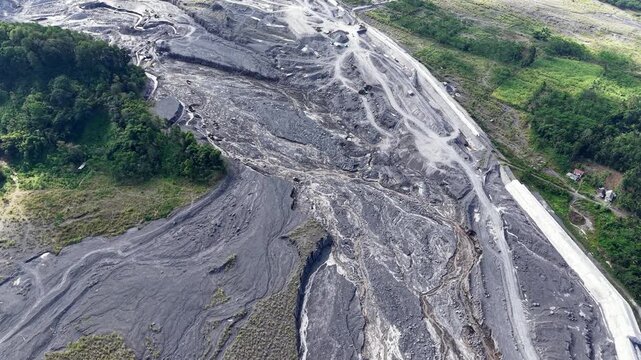 Top down sky perspective capturing the abstract patterns of a solidified, dry volcanic mudflow path cutting through the earth.