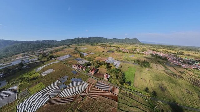 Drone fisheye aerial view of Teras Semeru terraces, farmland, and village under clear blue sky.