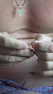 Fishing sinker attachment features a shirtless man securing weight to a thin line. Extreme close-up shot.