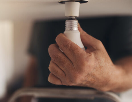 Hand changing lightbulb in ceiling fixture at home